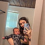 Dayton joined the competition — help win amazing prizes! baby, woman, mirror, selfie, bathroom, window, blinds, wooden_ceiling, phone, camouflage_clothing, holding, reflection, young_adult, casual_clothing, interior, portrait, infant, hand, face, smile
