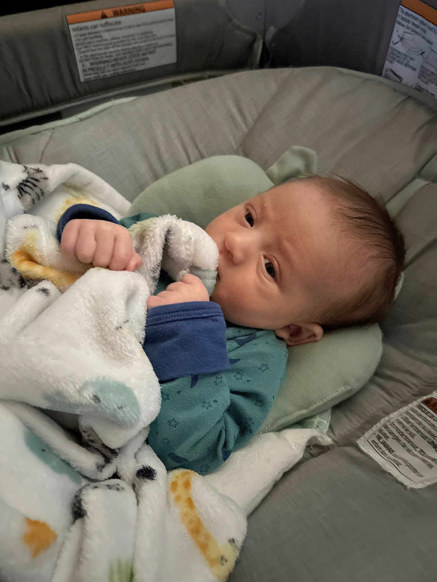 Dayton is registered to the contest to win money with this photo: baby, blanket, infant, cushion, seat, clothing, hand, face, person, indoor, soft, comfort, sleepwear, newborn, cute, resting, texture, pattern, warning_label, closeup