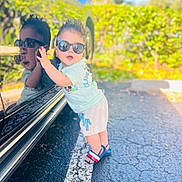 Bryan joined the competition — help win amazing prizes! toddler, child, sunglasses, reflection, car, parking_lot, outdoor, sunlight, greenery, pavement, clothing, shorts, sandals, cute, portrait, happy, person, summer, casual, fashion