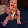Harper is registered to the contest to win money with this photo: baby, infant, pacifier, pink_clothing, socks, bed, blanket, indoor, door, person, child, cute, blue_bedspread, sitting, young, face, expression, curious, wearing, holding
