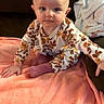 Harper is registered to the contest to win money with this photo: baby, child, infant, sitting, blanket, pink_blanket, couch, floral_clothing, long_sleeves, socks, blue_eyes, indoor, cute, soft_texture, curious, portrait, young_child, cozy, warm_colors, home