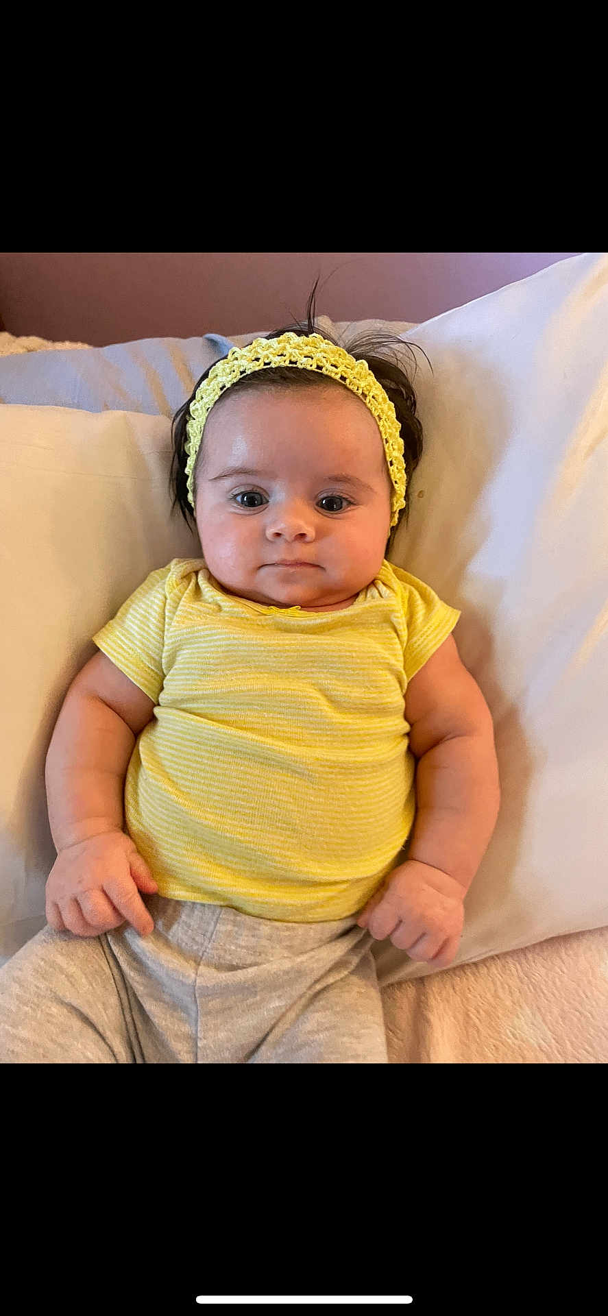 Sophia is registered to the contest to win money with this photo: baby, infant, child, yellow_headband, yellow_shirt, pillow, bed, cute, portrait, indoors, person, sleepwear, laying_down, soft_lighting, chubby_cheeks, short_sleeves, hand, face, looking_at_camera, young_child