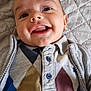 baby, smiling, face, child, clothing, argyle, quilted_blanket, happy, portrait, cute, young, infant, buttoned_shirt, sweater, lying_down, indoors, closeup, person, head, expression