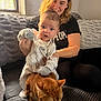 baby, woman, cat, indoor, couch, pajamas, smiling, pet, furniture, person, animal, child, cozy, window, blanket, hand, hair, face, living_room, curious