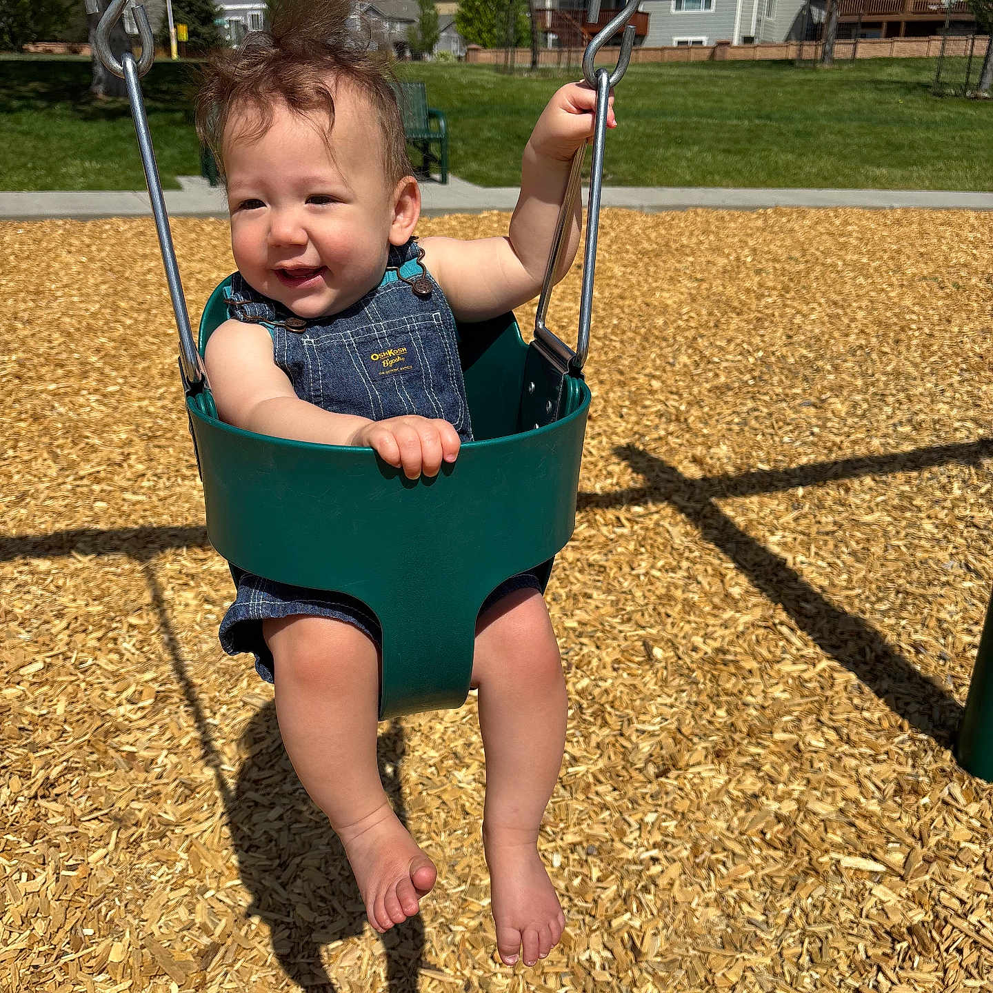 Danilo is registered to the contest to win money with this photo: toddler, child, swing, playground, sunny_day, outdoor, wood_chips, green_swing, happy, smiling, overalls, barefoot, grass, trees, houses, blue_sky, shadow, park, daylight, person