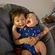 Danilo joined the competition — help win amazing prizes! toddler, baby, child, smiling, laughing, hugging, blue_clothing, indoor, chair, plush_toy, educational_poster, wall, carpet, person, cute, happy, sibling, family, playful, cozy