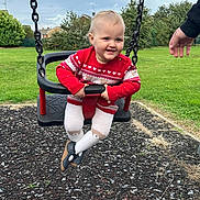 Lily joined the competition — help win amazing prizes! toddler, child, baby, smiling, happy, swing, playground, outdoor, portrait, red_sweater, white_tights, shoes, chains, adult_hand, grass, park, garden, suburban, sky, playground_surface
