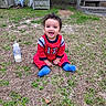 Axel joined the competition — help win amazing prizes! baby, child, grass, outdoor, milk_bottle, red_clothing, blue_socks, smiling, happy, sitting, porch, wooden_stairs, background, face, person, curly_hair, yard, daylight, casual, infant
