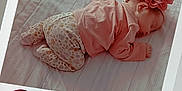 Lyana participe au concours pour gagner de l'argent avec cette photo : baby, sleeping, pink_clothing, headband, flower, bed, blanket, infant, polaroid, handwritten_date, cute, peaceful, child, newborn, soft_lighting, patterned_pants, toddler, resting, indoor, portrait