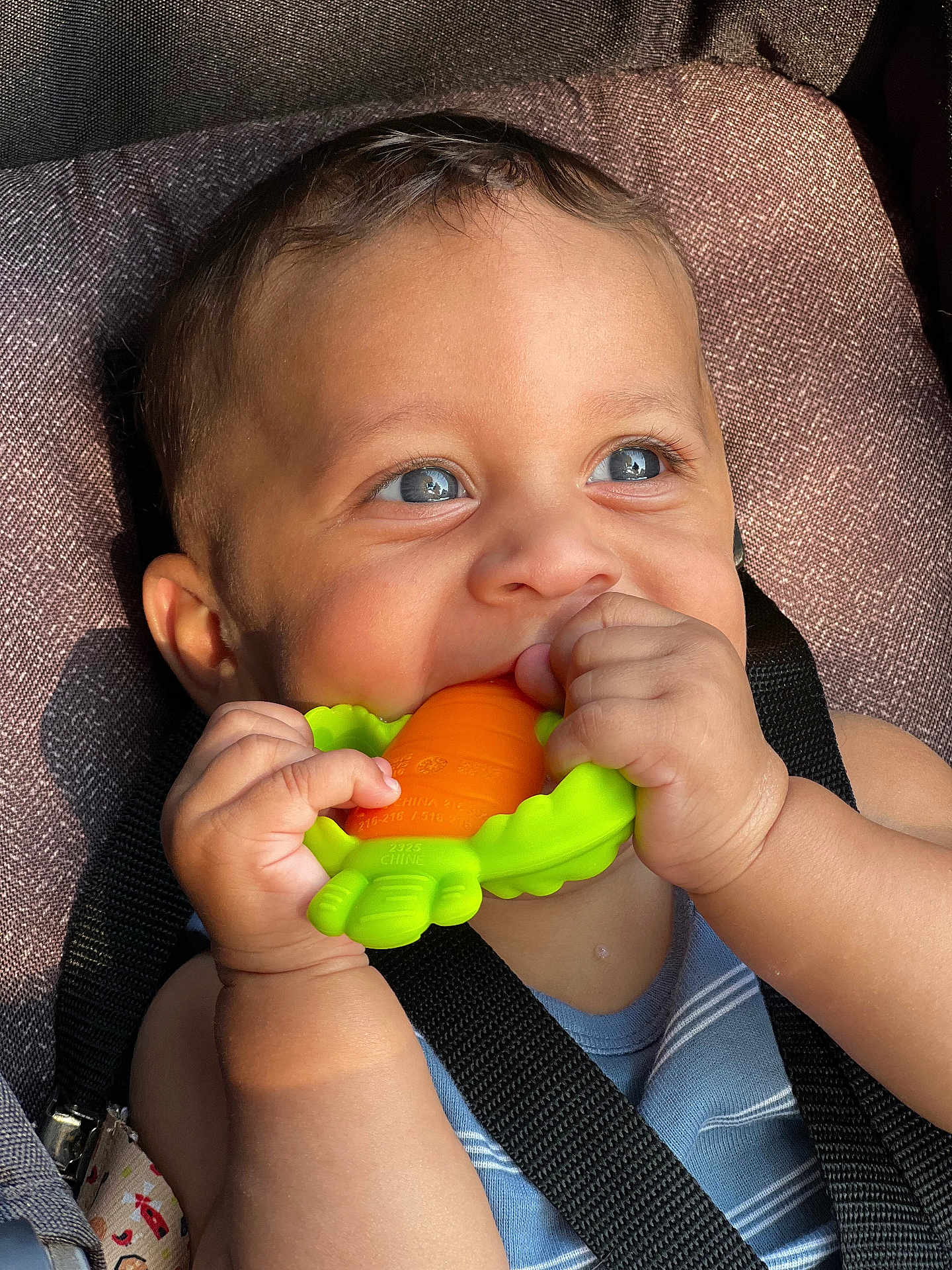 Jaylen is registered to the contest to win money with this photo: baby, child, blue_eyes, teething_toy, car_seat, straps, hand, face, smiling, happy, cute, infant, closeup, skin, clothing, sunlight, indoors, seat, person, portrait