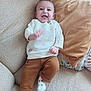 baby, child, smiling, couch, pillow, sweater, pants, socks, indoor, happy, person, seated, infant, cozy, furniture, cute, portrait, home, relaxed, laughing