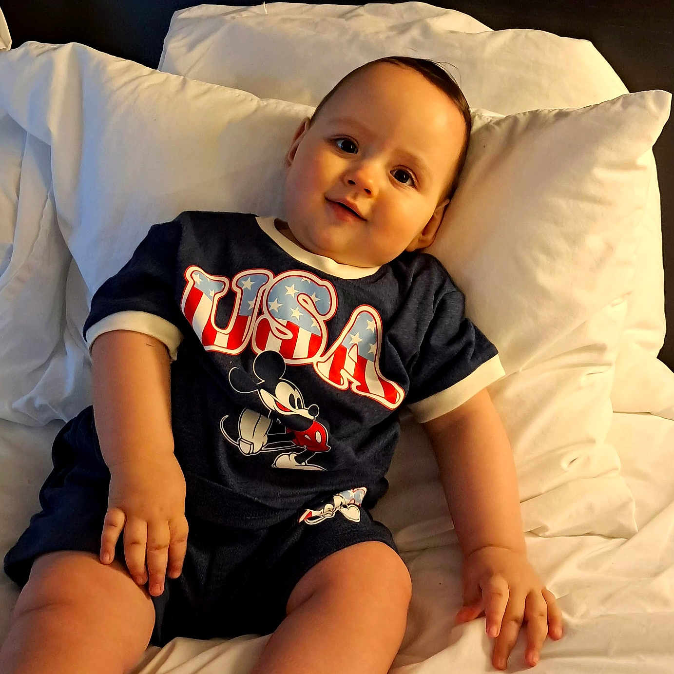 Ewan is registered to the contest to win money with this photo: baby, child, infant, smiling, portrait, bed, pillow, bedding, bedroom, indoor, sitting, lying_down, mickey_mouse, shirt, clothing, face, hands, legs, happy, photography