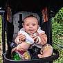 baby, bottle, child, clothing, cute, footwear, grass, greenery, happy, infant, nature, outdoor, person, playful, seatbelt, sitting, smiling, stroller, tongue_out, toy