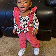 Aubrey joined the competition — help win amazing prizes! toddler, child, smiling, standing, pink_overalls, patterned_shirt, white_shoes, carpet, leather_couch, indoor, happy, portrait, earring, clothing, person, baby, cute, fashion, home, young_child