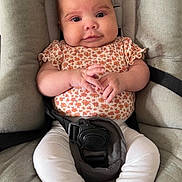 Olivia participe au concours pour gagner de l'argent avec cette photo : baby, infant, car_seat, cushion, clothing, white_leggings, socks, hands, face, head, cute, portrait, sitting, child, straps, safety_belt, indoors, expression, young, comfortable