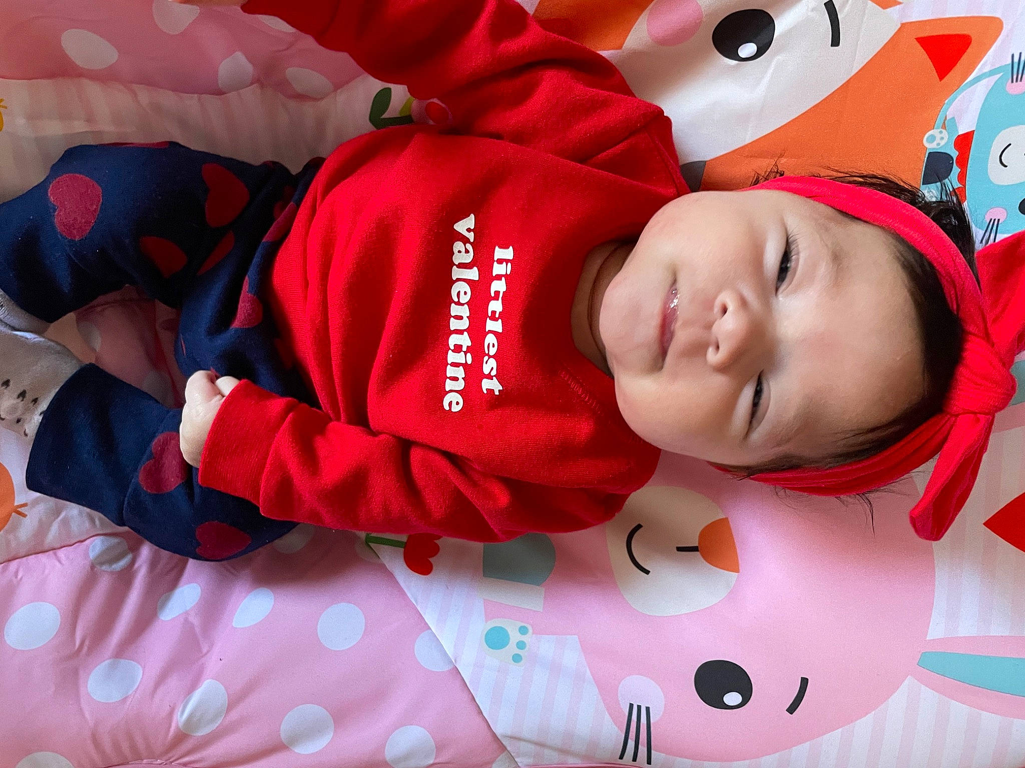 Kamila is registered to the contest to win money with this photo: baby, baby_toddler_clothing, carmine, child, comfort, facial_expression, happy, linens, magenta, mammal, pattern, person, pink, product, red, sleeve, smile, textile, toddler, vertebrate