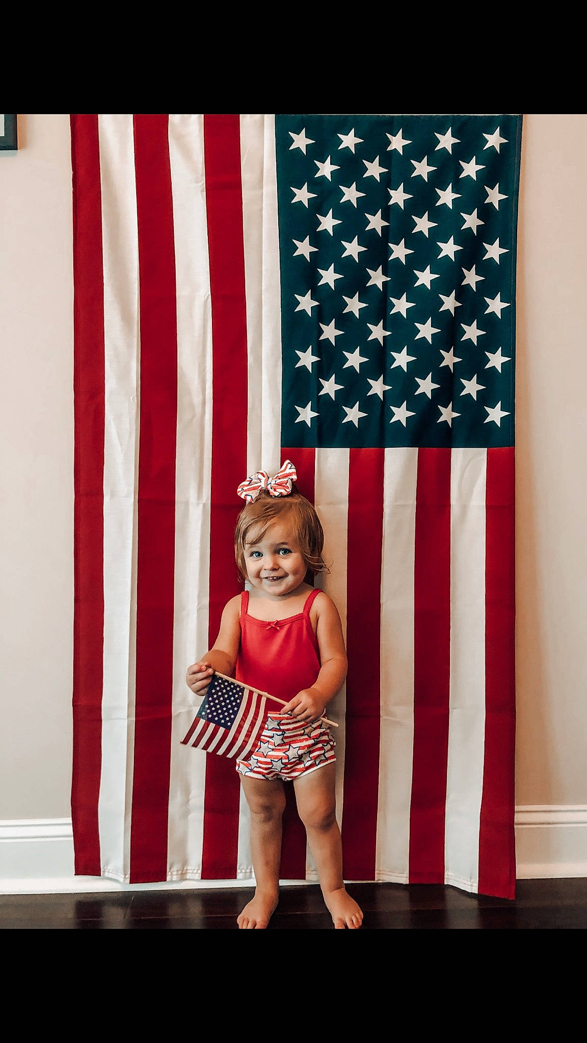 Felicity is registered to the contest to win money with this photo: child, curtain, flag, flag_of_the_united_states, interior_design, joy, pattern, person, photography, plant, red, room, textile, toddler, window