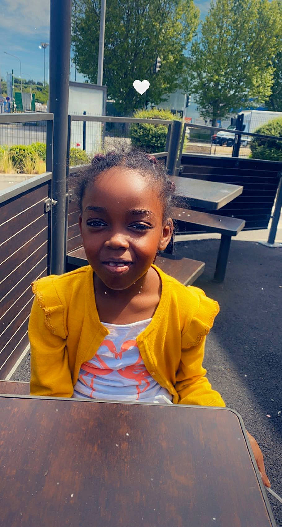 Adoniya participe au concours pour gagner de l'argent avec cette photo : asphalt, chair, child, eye, face, facial_expression, fun, hairstyle, happy, joy, leisure, person, plant, public_space, sitting, smile, standing, t_shirt, toddler, tree