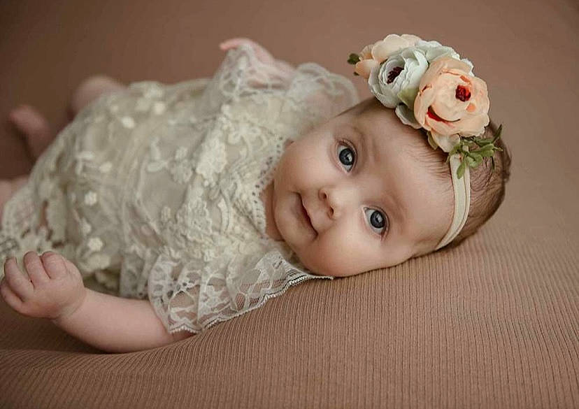 Everly is registered to the contest to win money with this photo: baby, baby_toddler_clothing, chin, dress, embellishment, eye, eyebrow, eyelash, face, flash_photography, happy, head, headpiece, human_body, iris, lip, person, petal, skin, sleeve