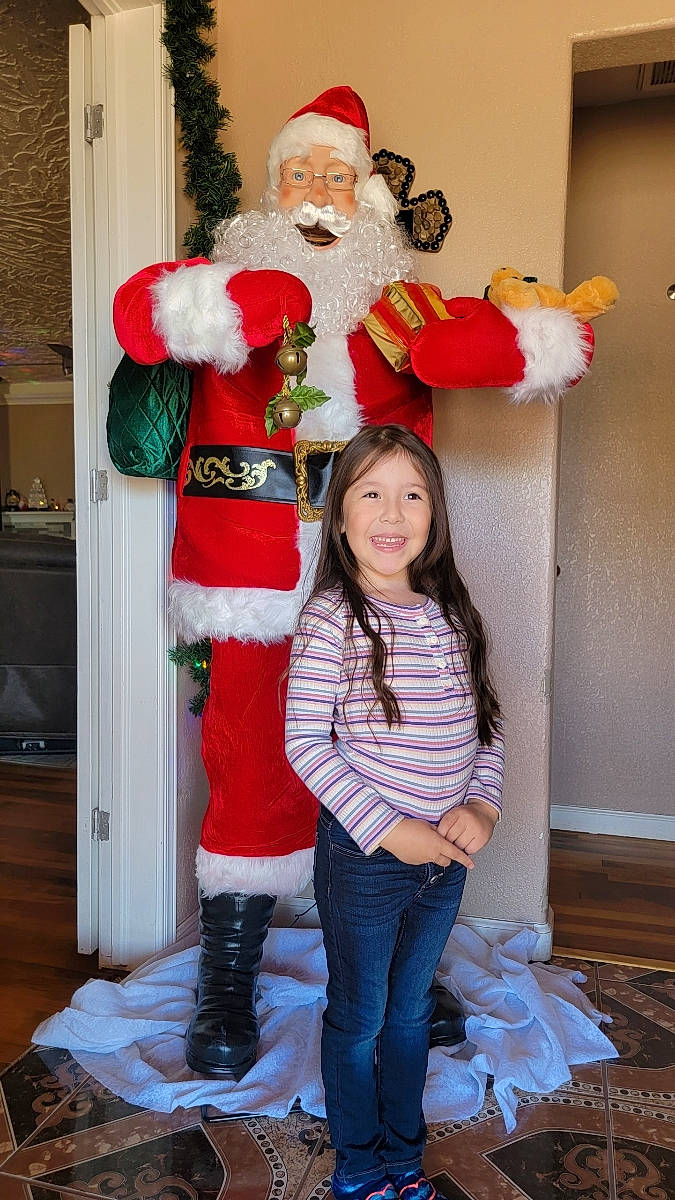 Noellani is registered to the contest to win money with this photo: beard, christmas, christmas_eve, event, face, fictional_character, fun, fur, happy, hat, head, holiday, human_body, joy, lap, person, red, santa_claus, smile, standing