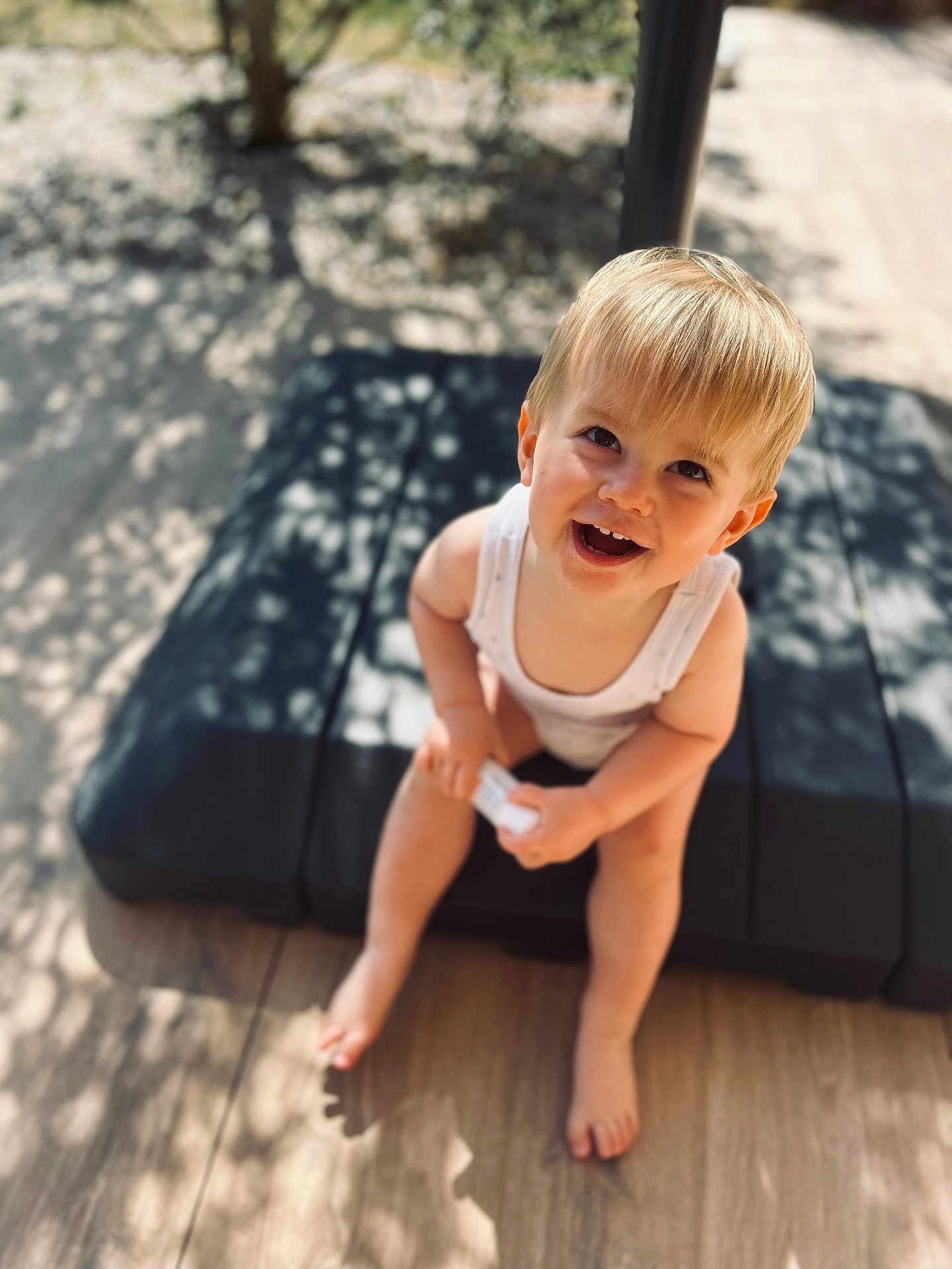 Malo participe au concours pour gagner de l'argent avec cette photo : background_blur, barefoot, blonde_hair, child, cushion, cute, daylight, face, happy, nature, outdoor, person, shadow, sitting, small_object, smiling, sunlight, toddler, white_clothing, wood_floor