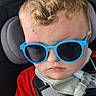 Bryant joined the competition — help win amazing prizes! toddler, child, sunglasses, car_seat, red_shirt, curly_hair, breathing_tube, medical_equipment, seatbelt, serious_face, indoors, portrait, person, baby, closeup, head, hair, clothing, transportation, safety