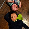 child, children, floor, wooden_floor, lying_down, medical_device, breathing_tube, neck_support, indoor, casual_clothing, portrait, two_people, face, young, relaxed, candid, friendship, healthcare, home, diverse