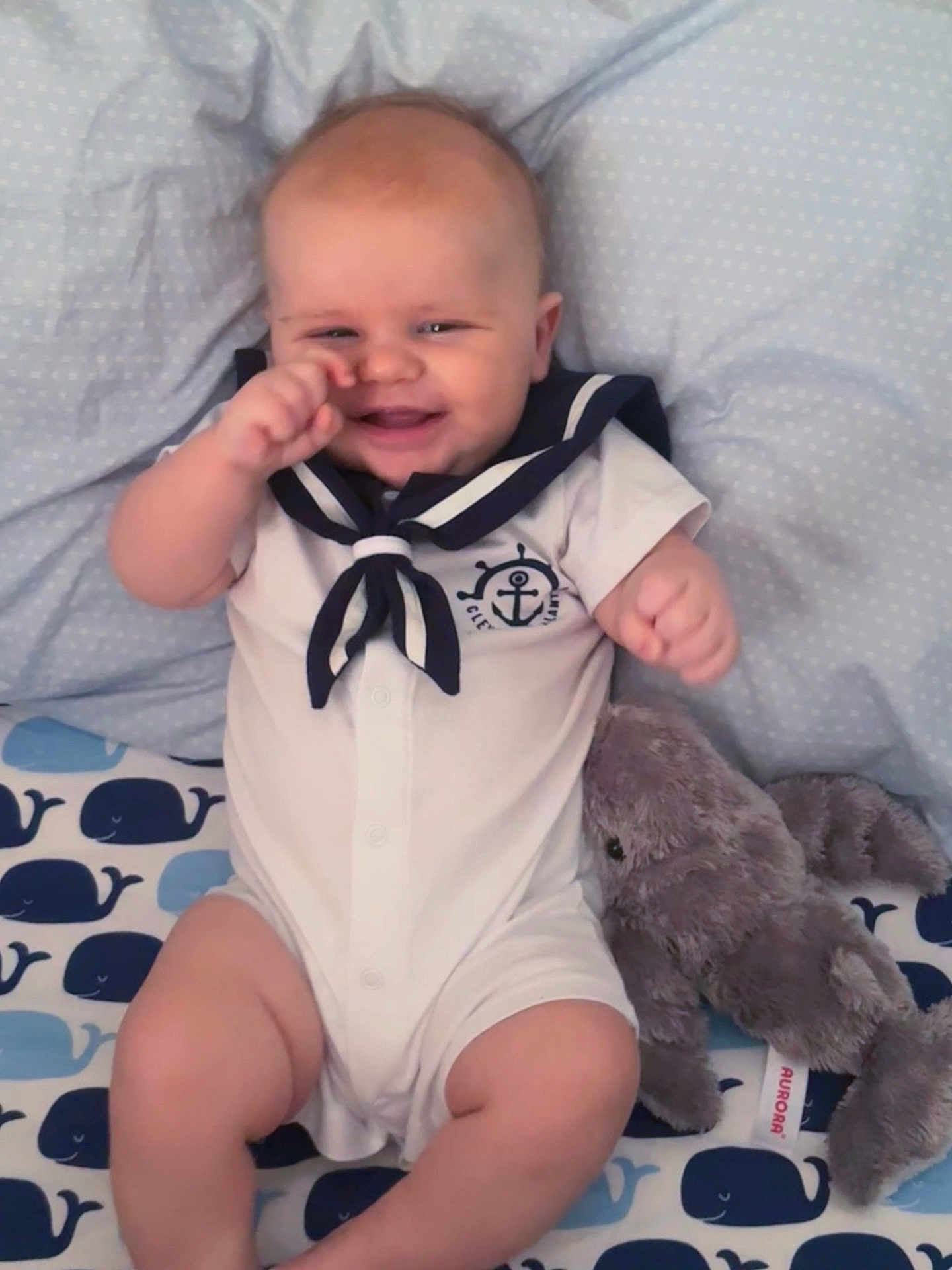Ryker joined the competition — help win amazing prizes! baby, infant, smiling, sailor_outfit, plush_toy, elephant_plush, blanket, whale_pattern, cute, child, happy, indoors, clothing, soft_toy, toddler, seated, person, portrait, playful, cozy