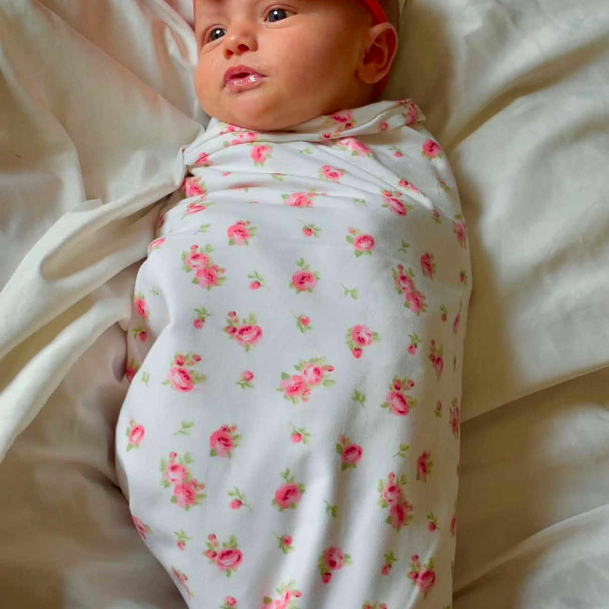 Kasey is registered to the contest to win money with this photo: baby, infant, swaddle, pink_bow, headband, floral_pattern, bed, white_bedding, cute, newborn, portrait, child, lying_down, soft_light, indoors, small_face, peaceful, wrapped, sleepwear, adorable