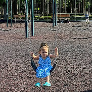 Emily is registered to the contest to win money with this photo: child, girl, swing, playground, blue_dress, turquoise_shoes, rubber_mulch, trees, sunny_day, outdoor, park, play_equipment, child_playing, person, summer, recreation, fun, daylight, casual_clothing, young_child