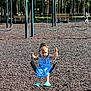 child, girl, swing, playground, blue_dress, turquoise_shoes, rubber_mulch, trees, sunny_day, outdoor, park, play_equipment, child_playing, person, summer, recreation, fun, daylight, casual_clothing, young_child