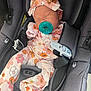 newborn, baby, car_seat, pacifier, sleeping, infant, headband, clothing, patterned_outfit, safety_harness, cute, resting, child, seatbelt, fabric, textile, orange, pink, gray, indoors