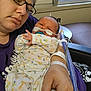 Jeremiah joined the competition — help win amazing prizes! woman, baby, newborn, hospital, medical_tubes, glasses, purple_shirt, window, hospital_room, bed, patient_wristband, infant_clothing, giraffe_pattern, holding, care, close_up, portrait, indoor, mother, child