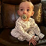 baby, pacifier, pajamas, child, infant, leather_chair, sitting, indoor, cute, young_child, person, small_hands, curious, face, head, eyes, furniture, home, comfort, cozy