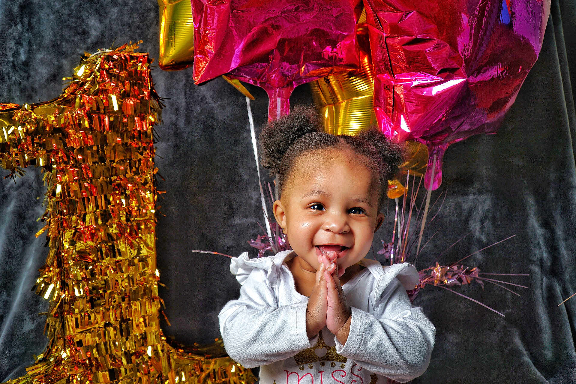 Amaya is registered to the contest to win money with this photo: toddler, child, smiling, happy, birthday, balloons, number_one, celebration, party, gold, pink, clothing, face, hands, hair, indoor, portrait, cute, festive, joyful