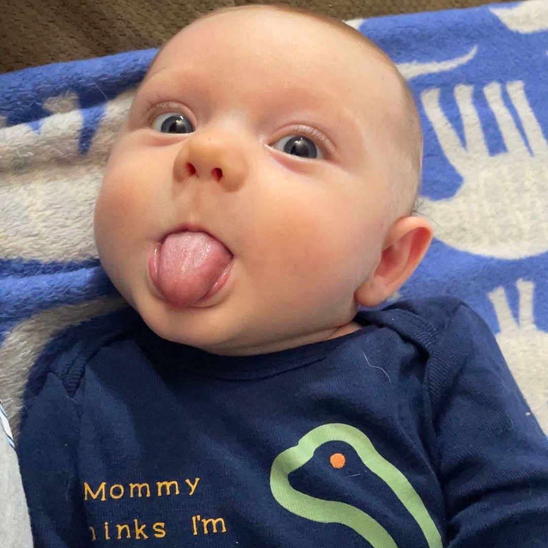 Asher is registered to the contest to win money with this photo: baby, bodypart, clothing, couch, cushion, face, furniture, happy, head, homedecor, mouth, newborn, person, photography, portrait, quilt, selfie, t_shirt, teeth, tongue