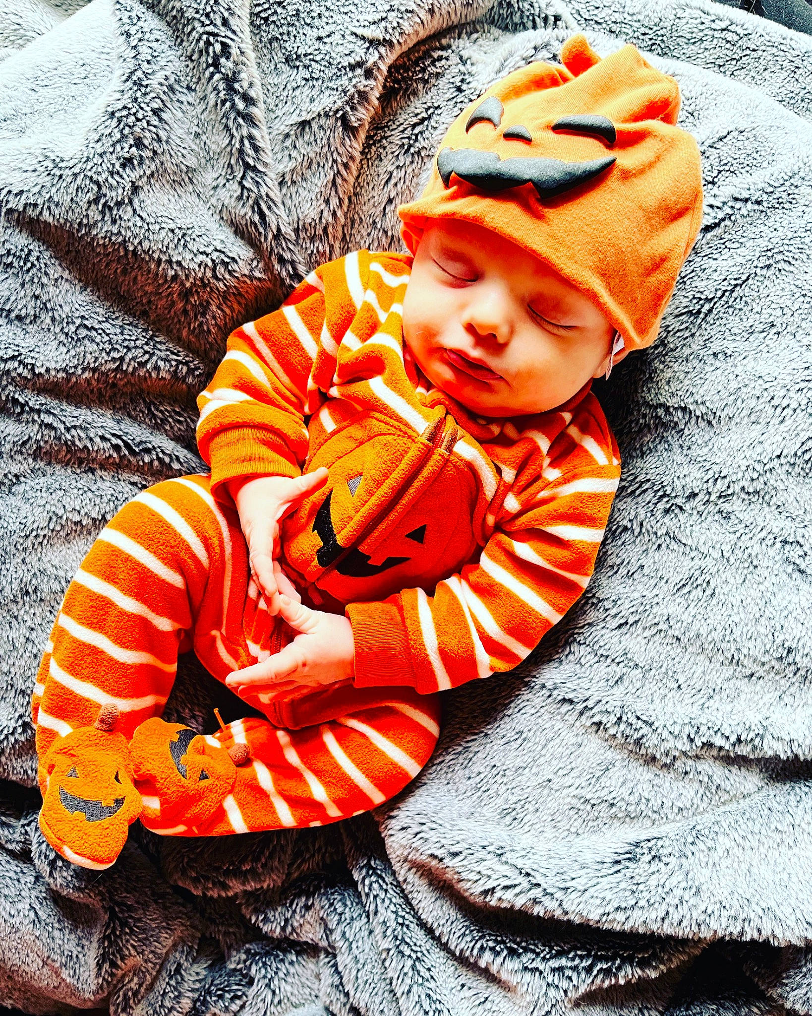 Cass is registered to the contest to win money with this photo: baby, baby_toddler_clothing, beanie, cap, child, comfort, fashion_accessory, fur, headgear, headwear, knit_cap, orange, pattern, person, plant, portrait_photography, sitting, sleeve, toddler, tree