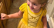 Paisley Mae joined the competition — help win amazing prizes! child, toddler, girl, portrait, smiling, happy, yellow_dress, hair_bow, blonde_hair, barefoot, indoor, kitchen, wooden_cabinets, tile_floor, rug, standing, looking_up, dress, bow, family_photo