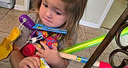 Paisley Mae joined the competition — help win amazing prizes! child, toddler, girl, portrait, face, hair, brown_hair, sitting, indoors, kitchen, tile_floor, toys, plush_toy, pacifier, toy_boat, toy_package, colorful, shopping, hands, home