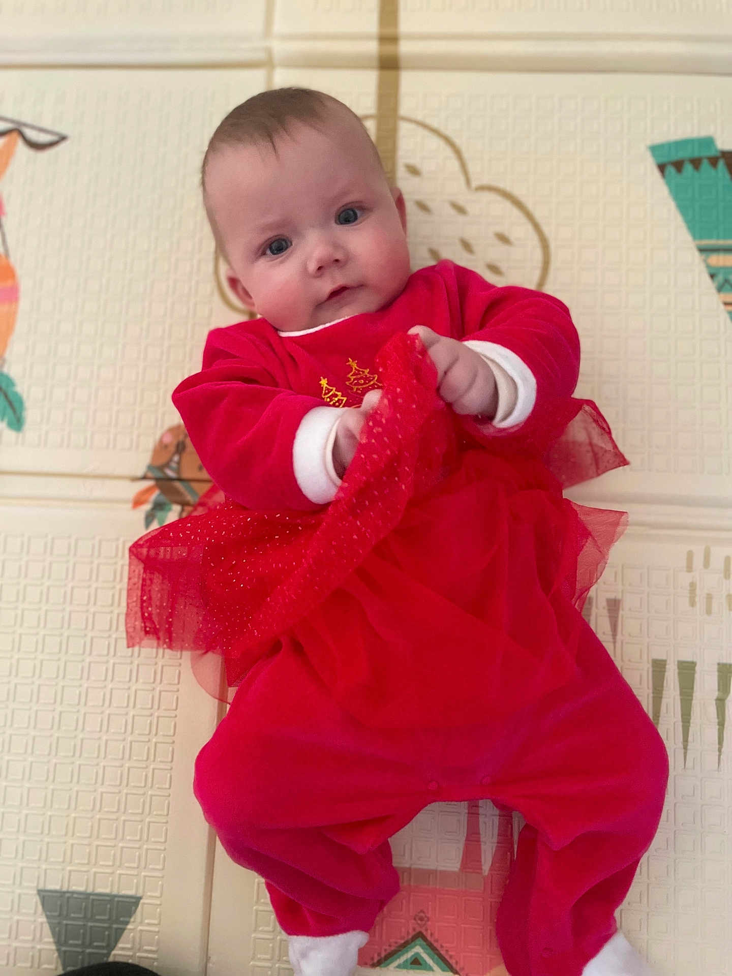 Romy a rejoint le concours — aidez-le/la à gagner de superbes lots ! baby, infant, red_clothing, play_mat, cute, child, indoors, face, hands, feet, fabric, pattern, soft_toys, young, portrait, looking_up, toddler, plush, comfort, lying_down
