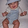 baby, child, smiling, happy, hat, striped_clothing, overalls, sitting, cute, infant, portrait, face, chubby_cheeks, white_background, soft_texture, hands, legs, casual_clothing, closeup, indoors