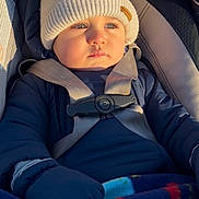 Axel is registered to the contest to win money with this photo: baby, child, car_seat, hat, winter_clothing, blanket, gloves, jacket, blue_eyes, outdoor, sunlight, warm, infant, portrait, seat_belt, cute, young, face, person, bundle