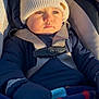 baby, child, car_seat, hat, winter_clothing, blanket, gloves, jacket, blue_eyes, outdoor, sunlight, warm, infant, portrait, seat_belt, cute, young, face, person, bundle