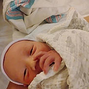 Taylon is registered to the contest to win money with this photo: baby, newborn, infant, blanket, bed, sleepy, hand, face, hospital_blanket, wrapped, cozy, soft, clothing, person, indoor, cute, resting, skin, headwear, human