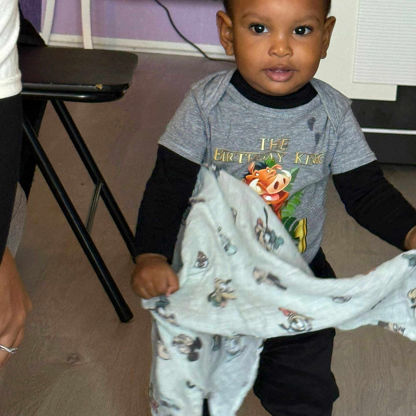 Djahnaël a rejoint le concours — aidez-le/la à gagner de superbes lots ! black_pants, blanket, braided_hair, cable, child, clothing, curious, expression, floor, furniture, home, indoor, person, portrait, shirt, standing, table, toddler, wall, young_child