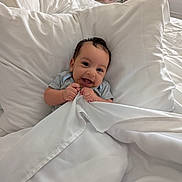 Zaki is registered to the contest to win money with this photo: baby, bed, blanket, child, comfort, cozy, cute, face, hand, happy, indoors, infant, person, pillow, resting, sheet, sleeping_area, smiling, soft, young