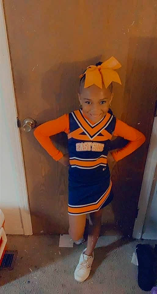 Imani is registered to the contest to win money with this photo: electric_blue, fashion_design, fictional_character, flooring, foot, fun, happy, hat, human_leg, joy, knee, mascot, orange, person, room, sandal, smile, stuffed_toy, thigh, toy