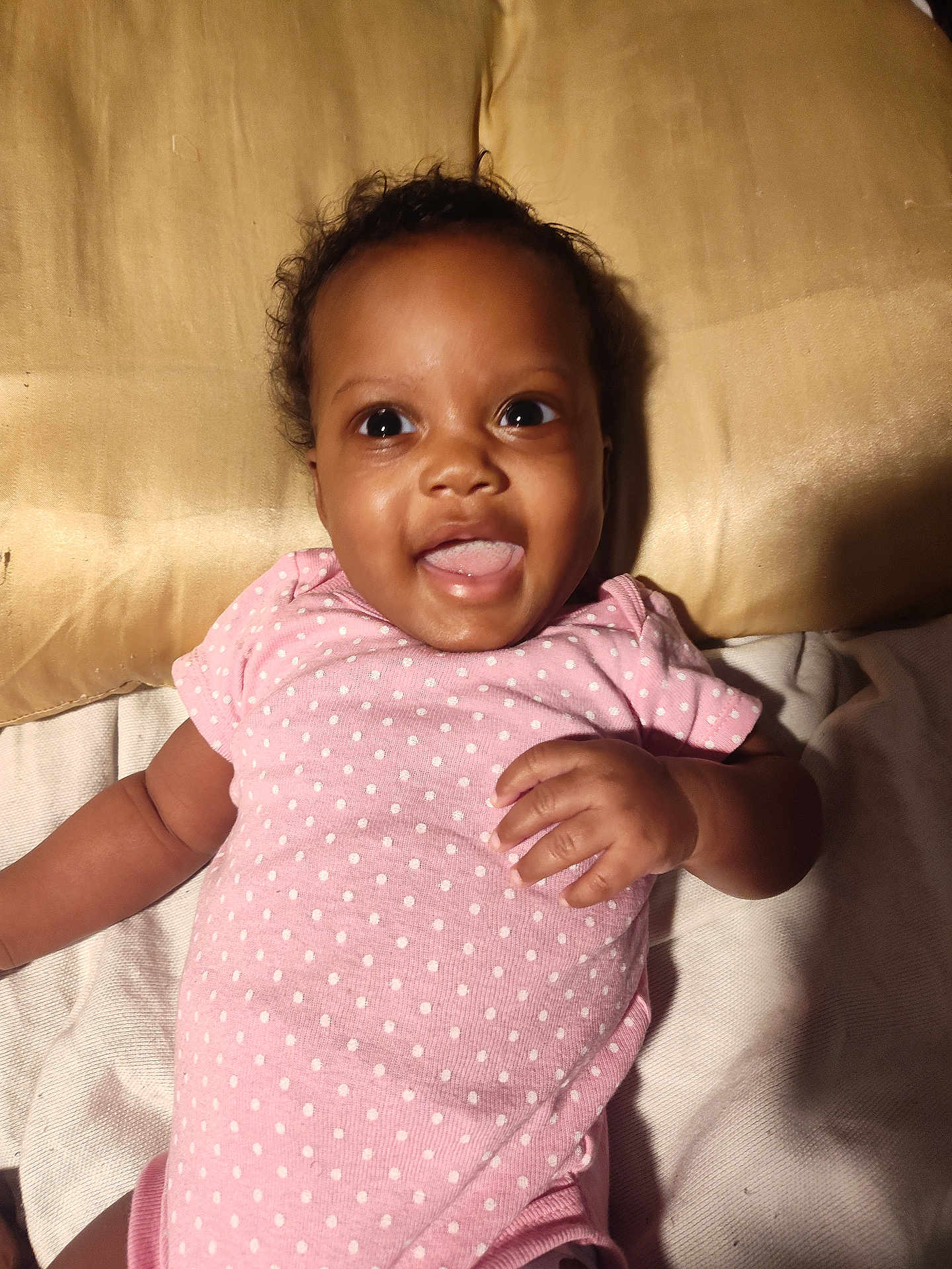 Miss'Minnie joined the competition — help win amazing prizes! baby, child, pink_onesie, polka_dots, tongue_out, smiling, lying_down, pillow, bed, cute, happy, infant, skin, hand, face, indoor, cozy, young_child, expression, portrait