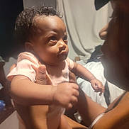 Miss'Minnie joined the competition — help win amazing prizes! baby, adult, holding, indoor, curly_hair, expression, face, skin, person, clothing, hand, arm, light, shadow, blurred_background, interaction, portrait, closeup, warm_tone, intimate