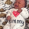baby, infant, smiling, onesie, clothing, pattern, leopard_print, heart, blanket, happy, cute, sleepwear, child, face, fist, young, lying_down, adorable, joyful, indoor